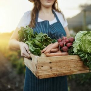 Femme qui tient un panier rempli de légumes frais